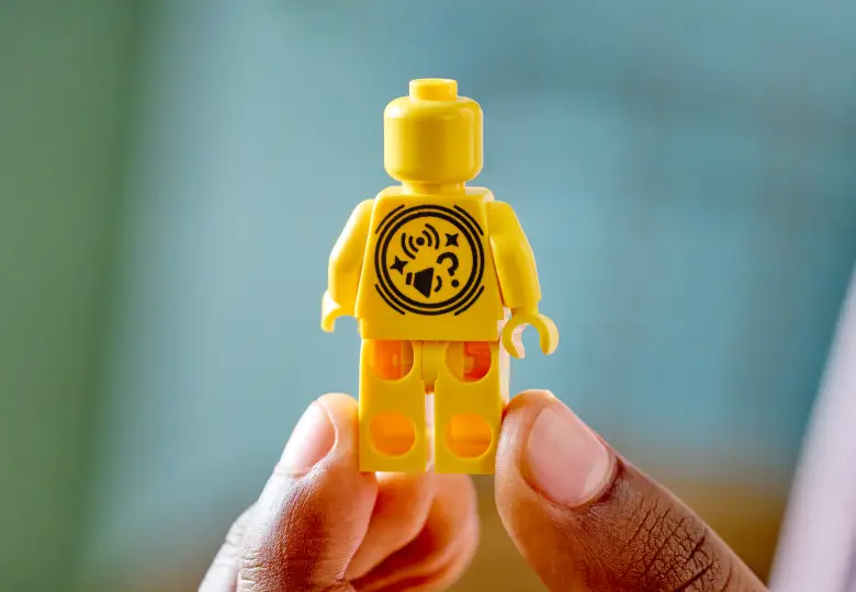 A yellow LEGO SMART Minifigure with the SMART symbol printed on its torso