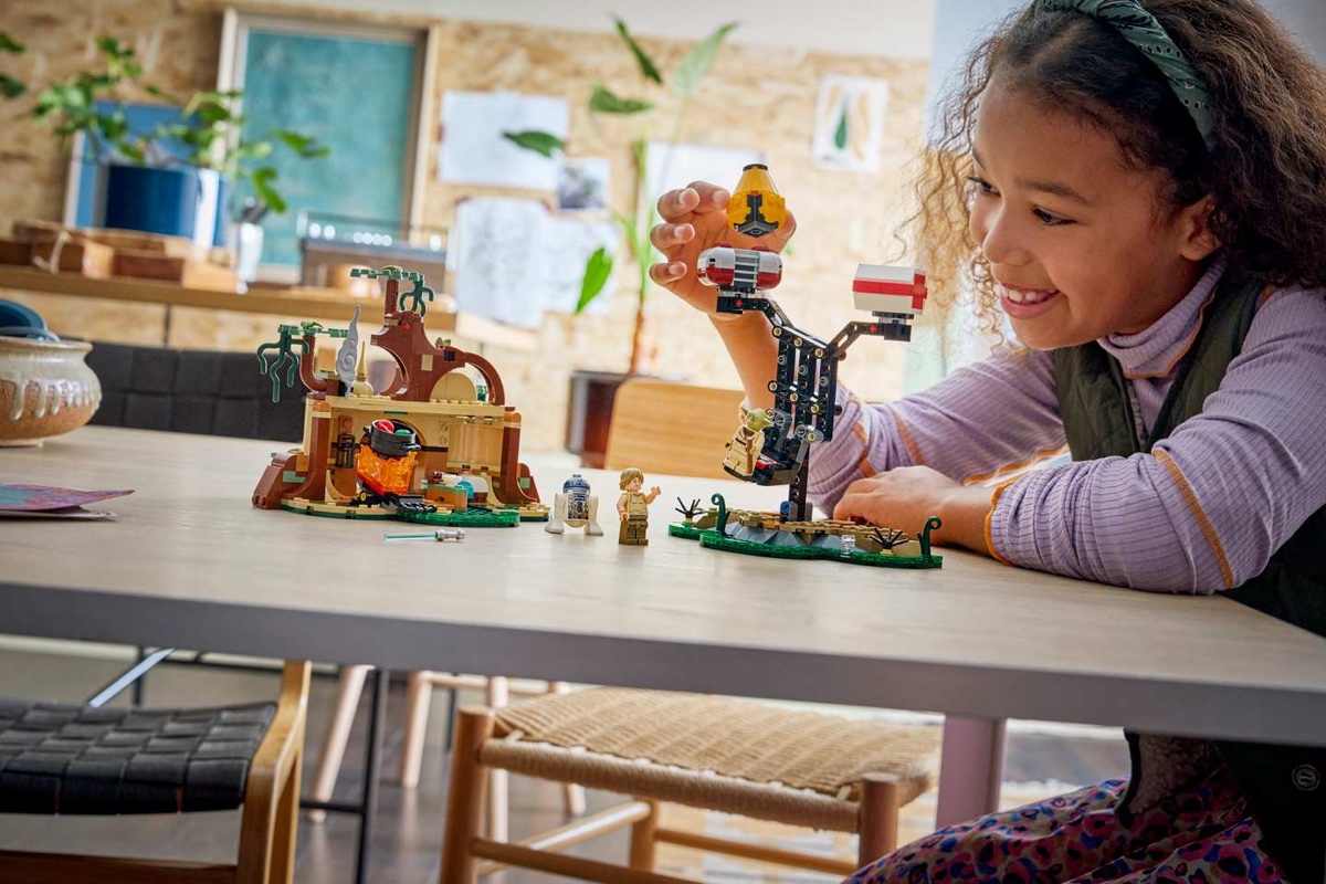 A girl playing with the LEGO Smart Play Yoda's Hut set, fully engaged in physical play without any screen nearby